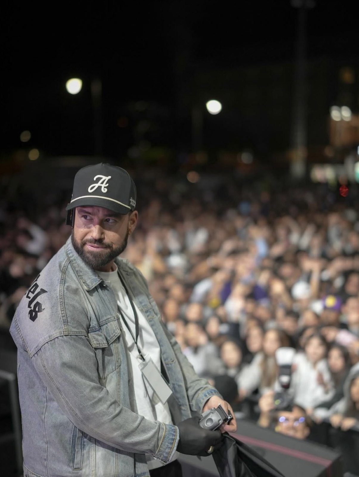 Artist standing on stage with a large outdoor crowd behind him