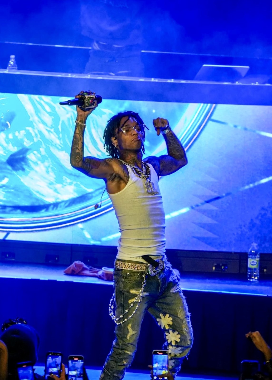 Performer raising a microphone under blue stage lighting