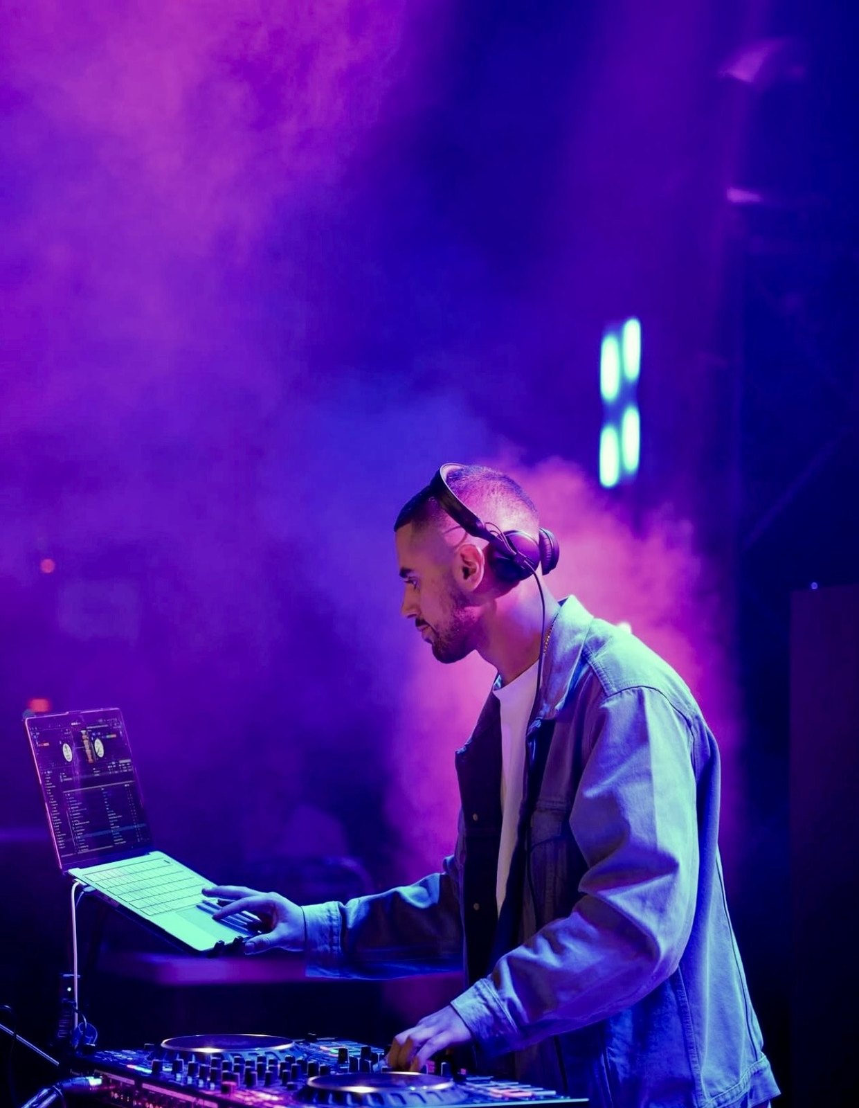 DJ performing at a mixer under purple stage lights