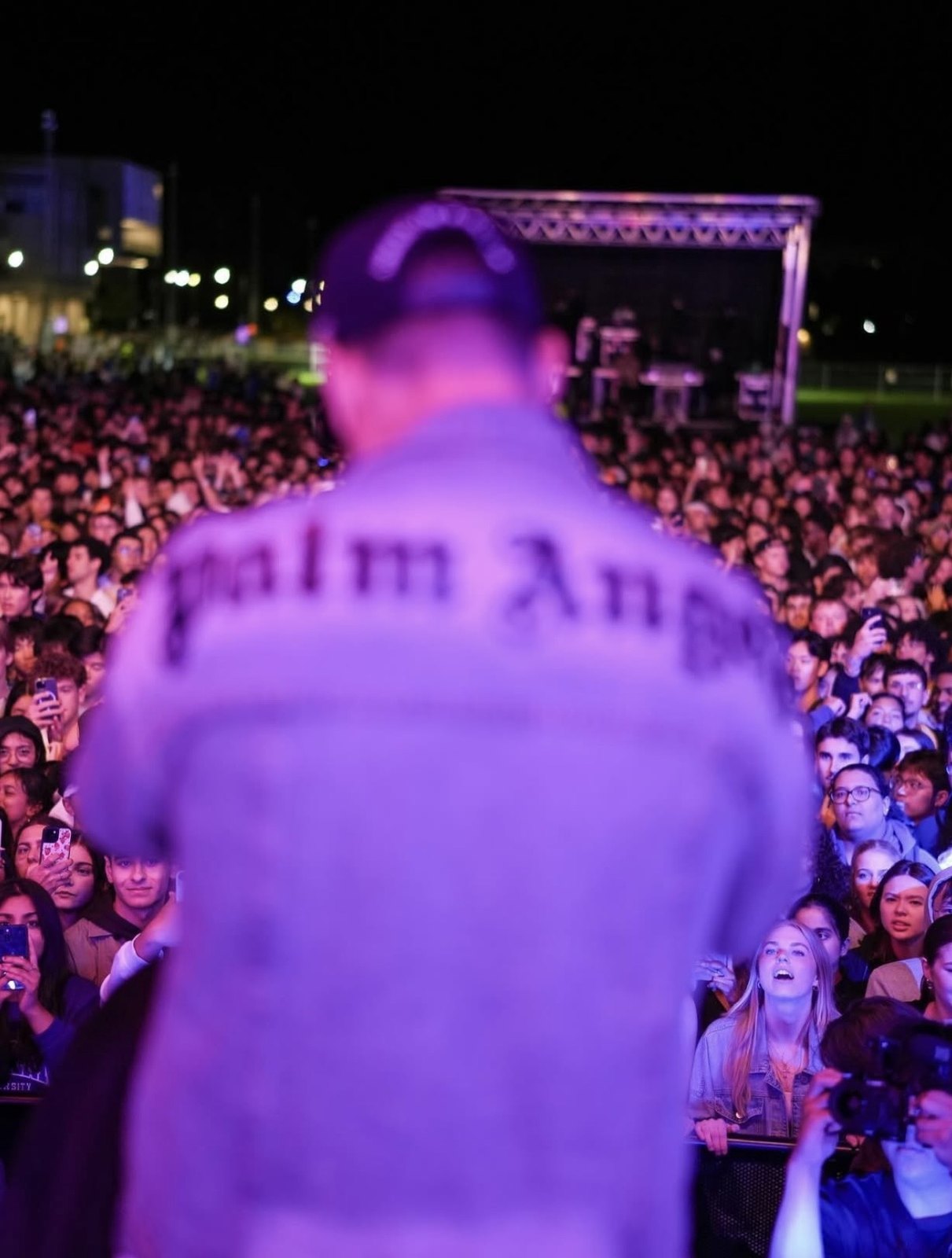 Performer photographed from behind while facing a festival crowd