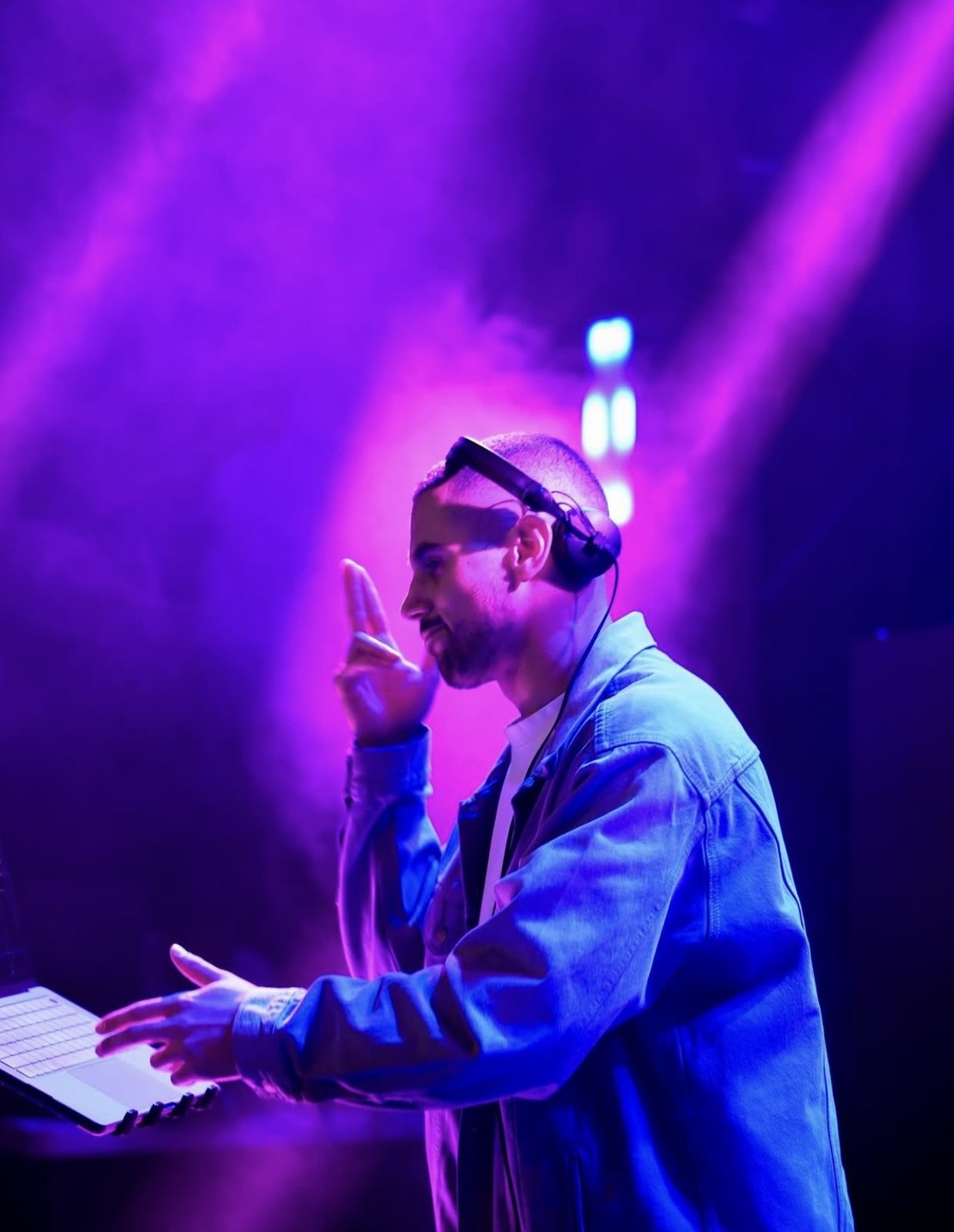 Musician performing at a keyboard under purple concert lighting