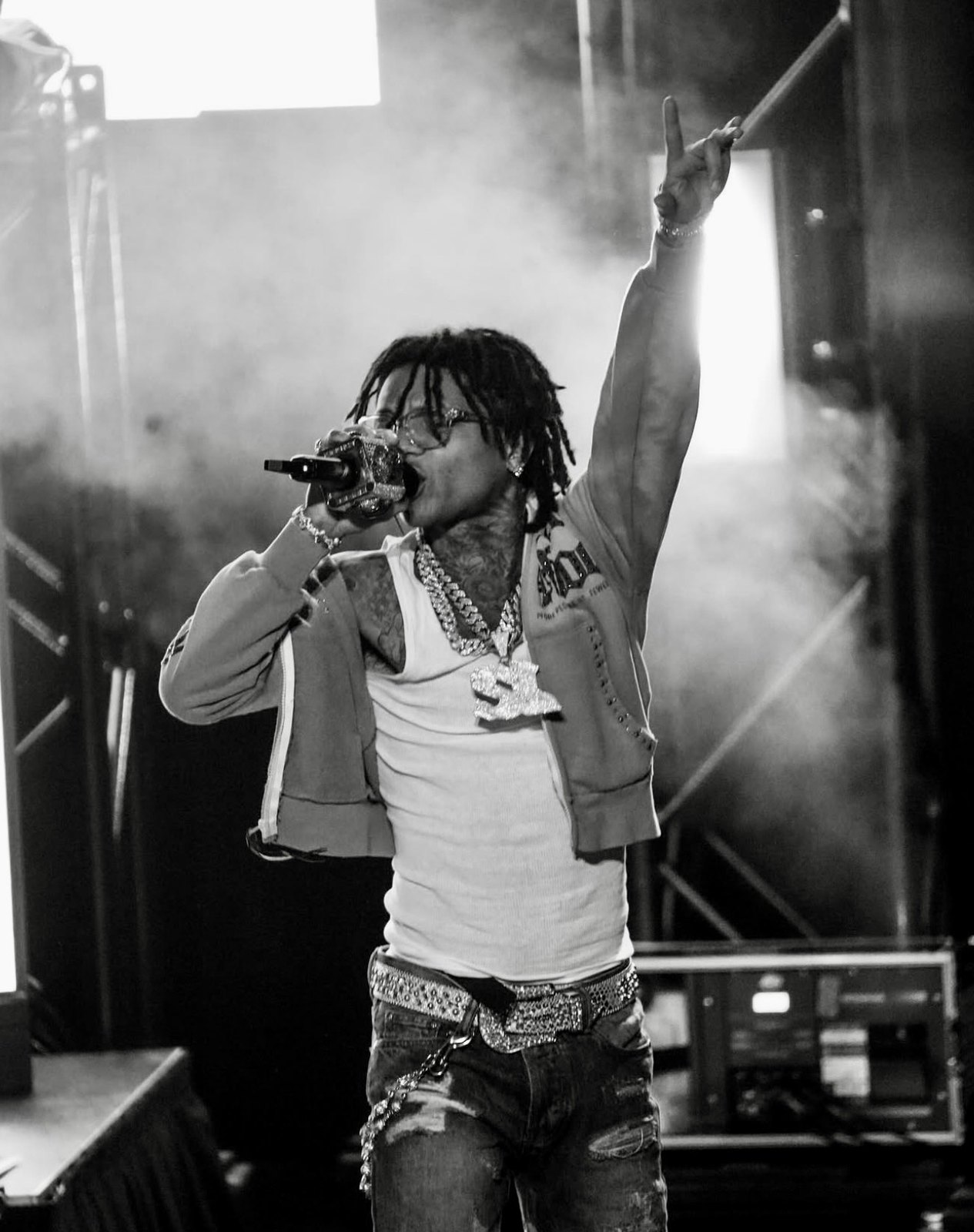 Live performer raising a microphone above the stage in black and white