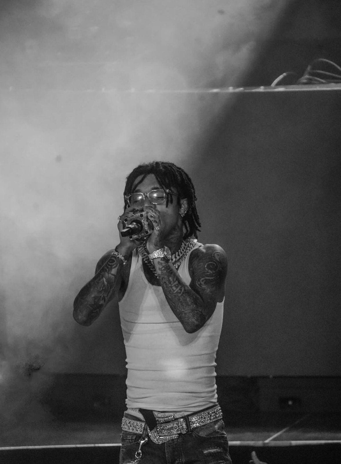 Black-and-white portrait of a vocalist performing through stage smoke