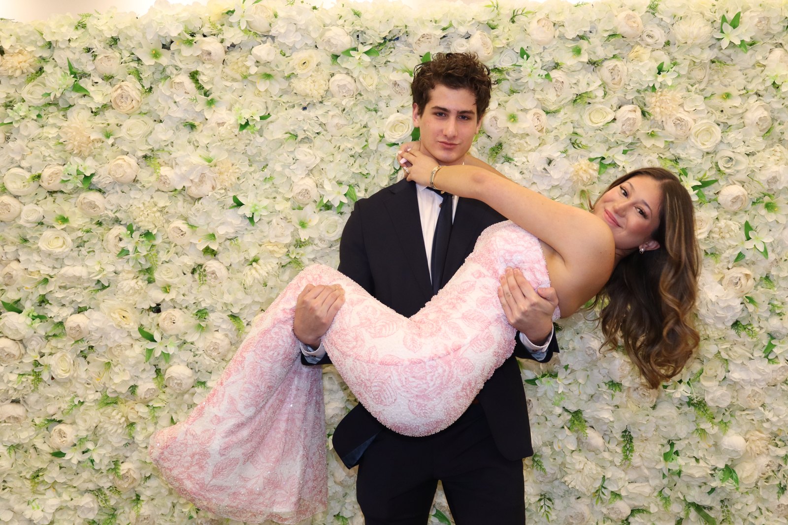 Guests posing in front of a cream flower wall