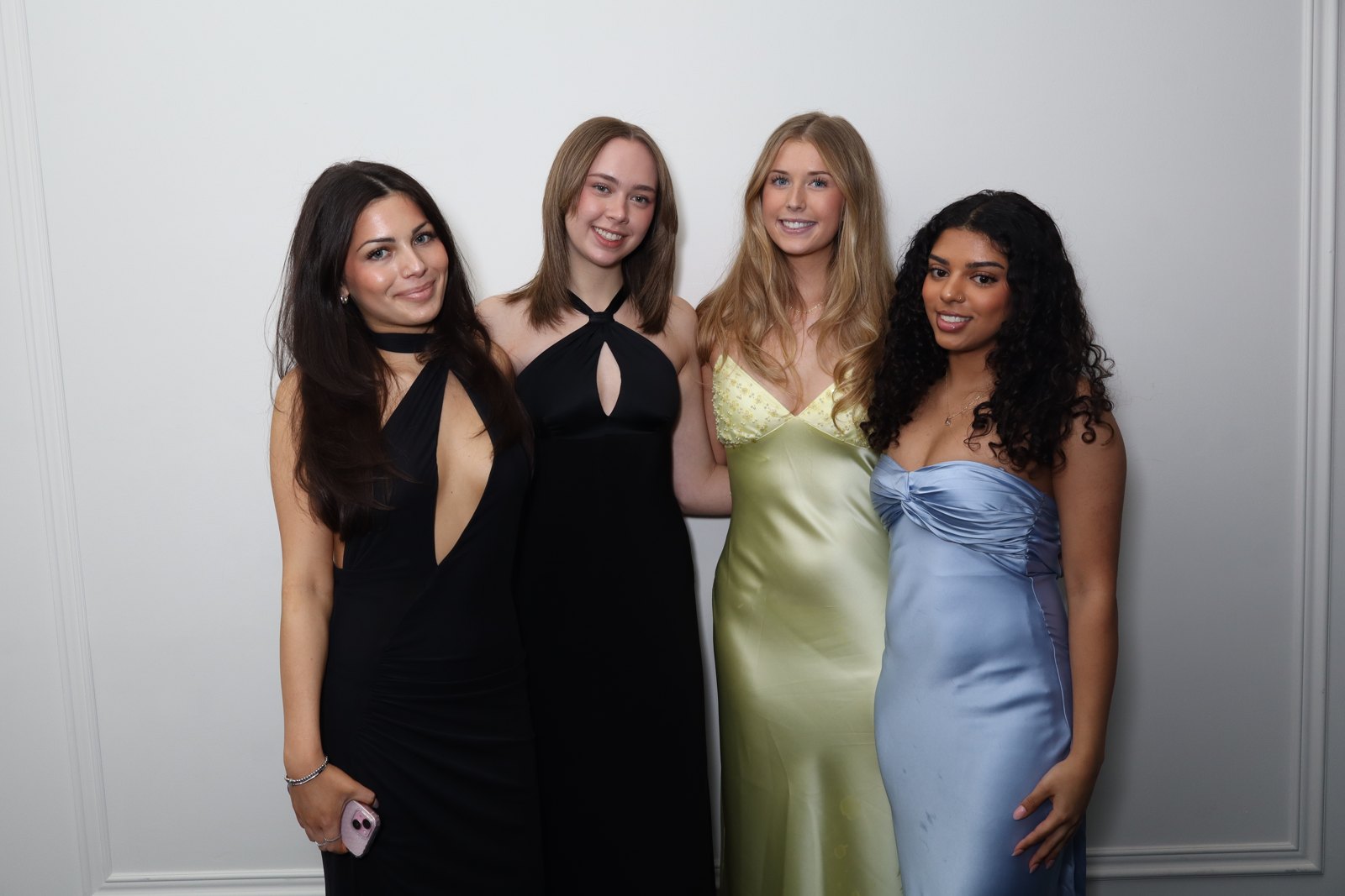 Four guests in formal dresses posing together